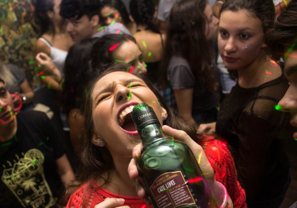 Vrouw in een menigte met een fles Catu Libre (Braziliaanse mixdrank)